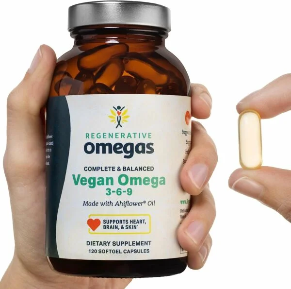 Hand holding pill bottle with another hand showing the size of a softgel held between two fingers