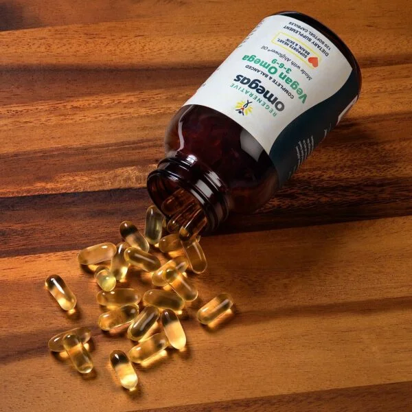 Pill bottle laying sideways with softgels spilled out onto a wood surface